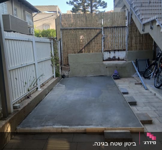 חצר עם ריצוף בטון חדש וגדרות עץ